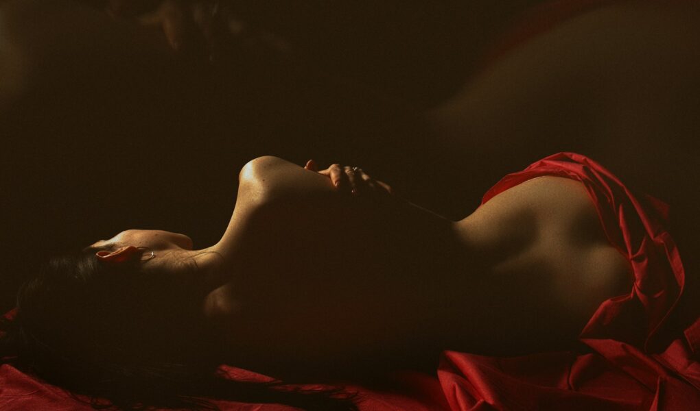 a woman in a red dress laying on a bed